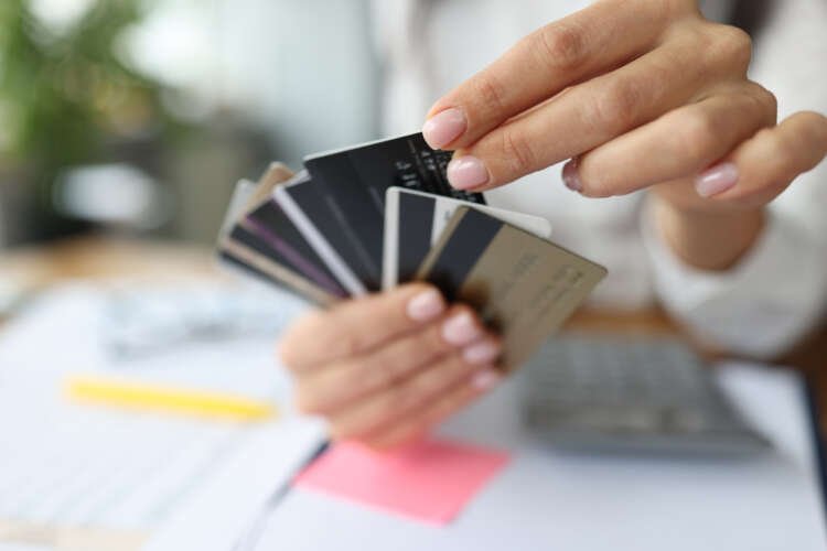 Fan of plastic credit cards is in woman’s hand.