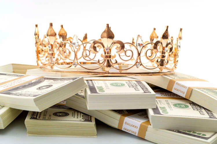 Gold crown on a pile of dollar bills symbolizes the importance of cash in banking - Global Banking & Finance Review