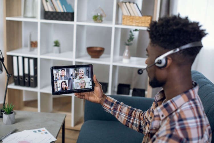 Afro guy engaged in video conference with diverse colleagues, fostering connectivity in remote teams - Global Banking & Finance Review