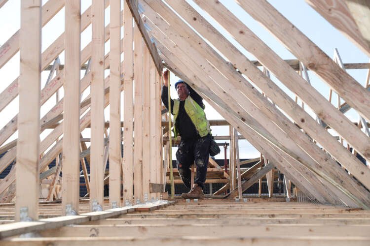 Builder working on a roof for Taylor Wimpey, reflecting housing market challenges - Global Banking & Finance Review
