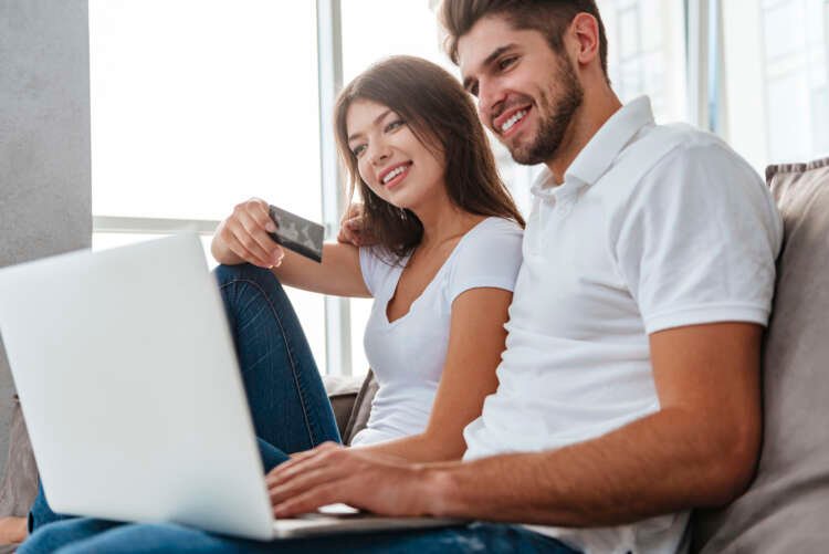 Happy young couple enjoying online shopping at home, illustrating localised global shopping experience - Global Banking & Finance Review