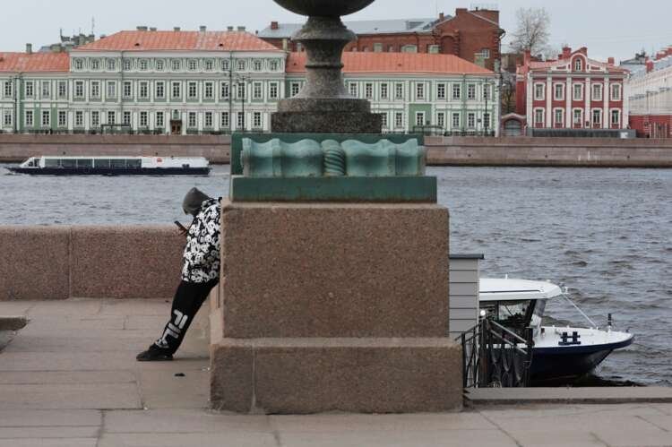 Man using smartphone on Neva River embankment in Saint Petersburg amid Russia's shifting smartphone market - Global Banking & Finance Review
