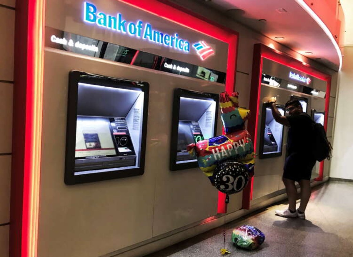 Man using ATM at Bank of America, reflecting banking profits and economic revival - Global Banking & Finance Review