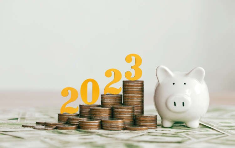 Gold wooden number 2023 atop coins and a piggy bank, symbolizing financial predictions for 2023 - Global Banking & Finance Review