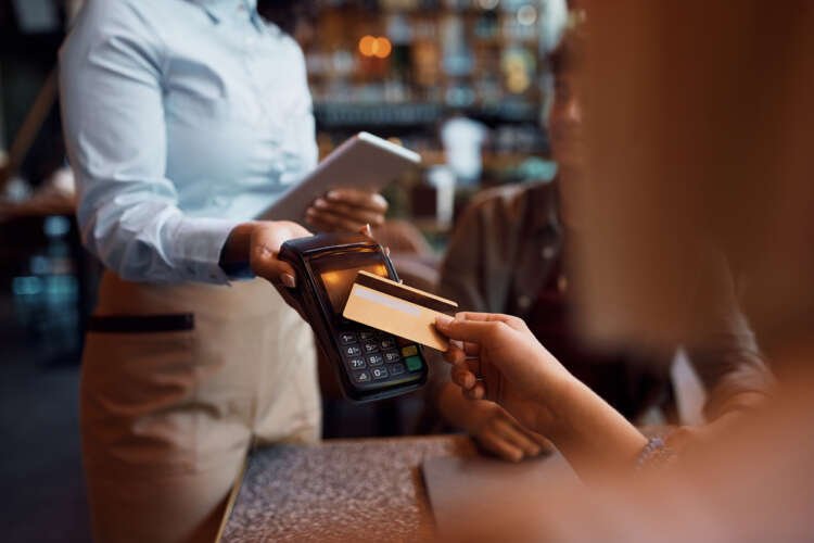 Close-up of a woman making a contactless payment with a credit card - How real-time payments shape the finance industry - Global Banking & Finance Review