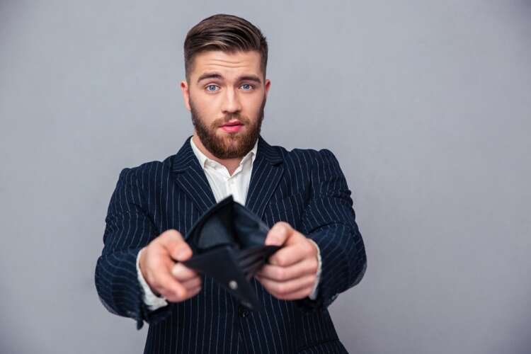 A businessman showing an empty wallet symbolizing financial struggles - Global Banking & Finance Review