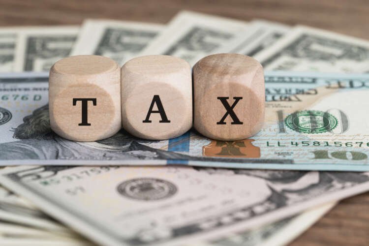 Wooden block with TAX letters on US dollar bills, reflecting R&D tax relief in finance - Global Banking & Finance Review