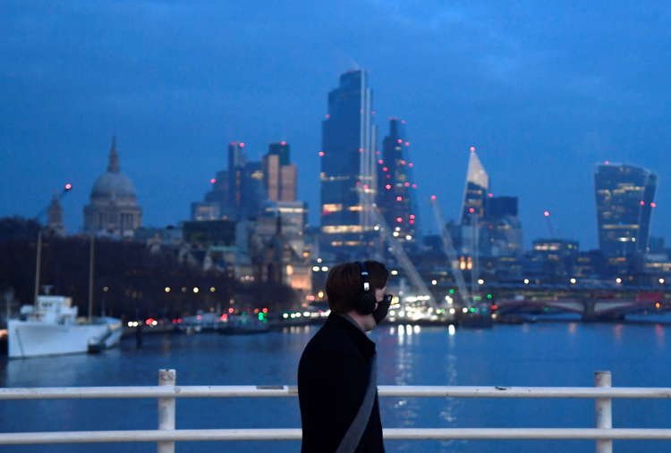 A man views the City of London skyline, symbolizing UK economic recovery and hiring trends - Global Banking & Finance Review