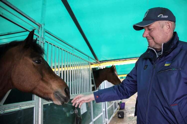 Parkhomchuk, founder of Ukrainian Equestrian Federation Charity Foundation pets a horse in a makeshift stable, in Lviv region