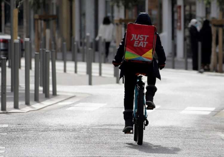 A Just Eat delivery cyclist navigating a city street amid financial news - Global Banking & Finance Review