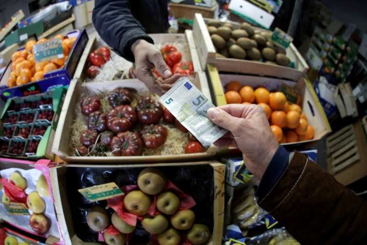 A shopper paying with Euro notes in a market, highlighting inflation relief efforts - Global Banking & Finance Review