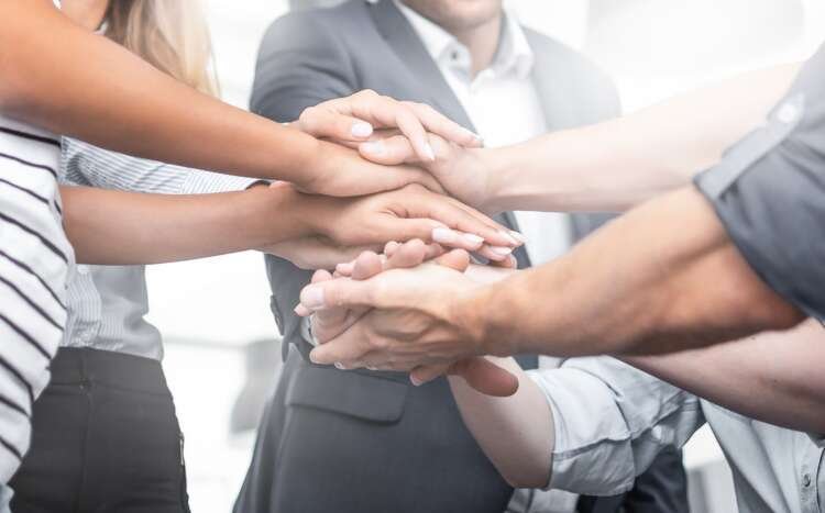 Diverse hands joining together symbolizing unity in facing economic challenges - Global Banking & Finance Review