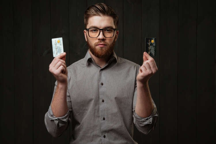 Serious bearded man holding credit cards, illustrating payment orchestration in aviation - Global Banking & Finance Review