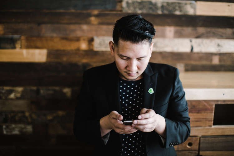 Asian man using a cell phone, representing banking technology - Global Banking & Finance Review