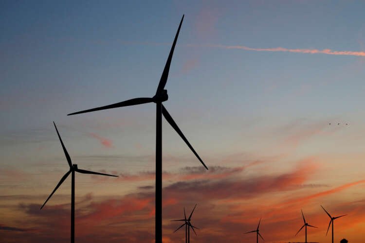 Power-generating wind turbines at sunset symbolize impact investing - Global Banking & Finance Review