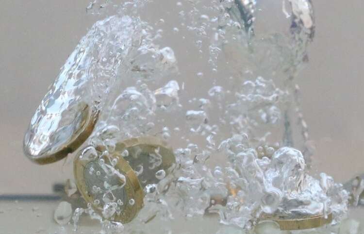 Illustration of UK pound coins falling into water, symbolizing decline amid political uncertainty - Global Banking & Finance Review