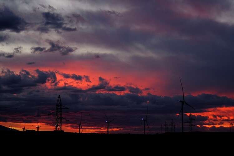 Wind turbines at sunset illustrating Holaluz's shift to green energy - Global Banking & Finance Review