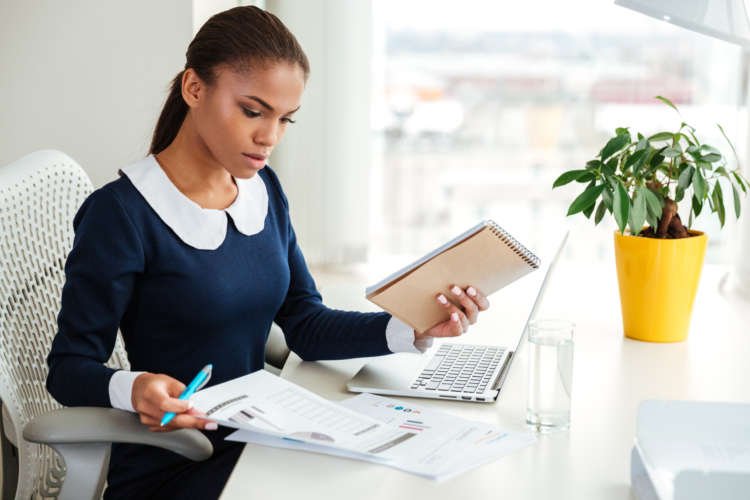 African business woman working on a laptop with documents, promoting productivity tips - Global Banking & Finance Review