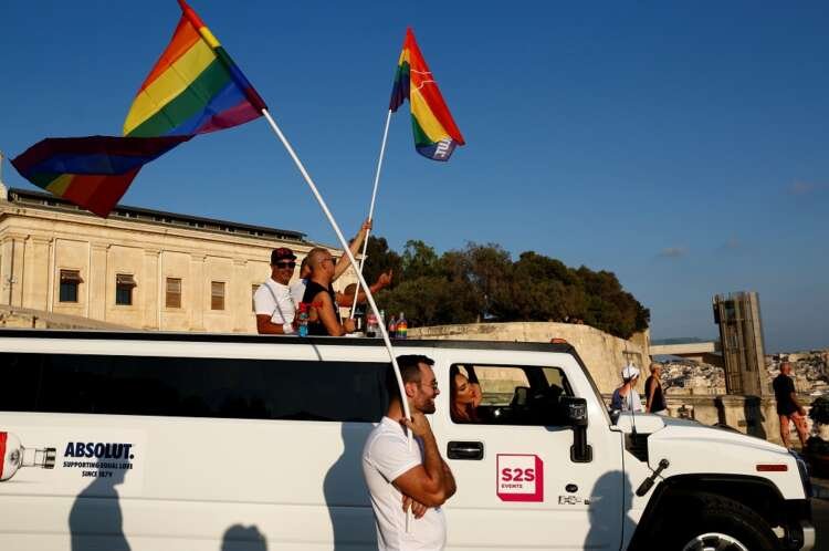 Participants wave rainbow flags from a Hummer Limousine during Malta Pride Parade - Global Banking & Finance Review