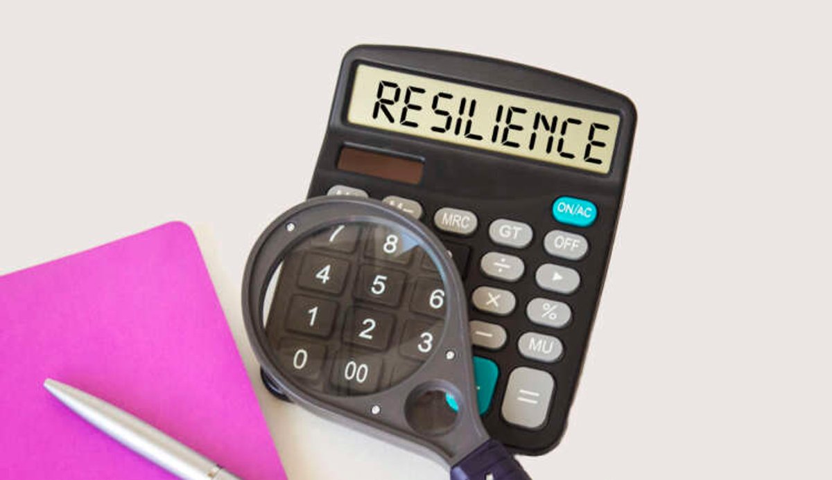 Calculator with resilience text, notepad, magnifying glass, and pen symbolizing finance strategies - Global Banking & Finance Review