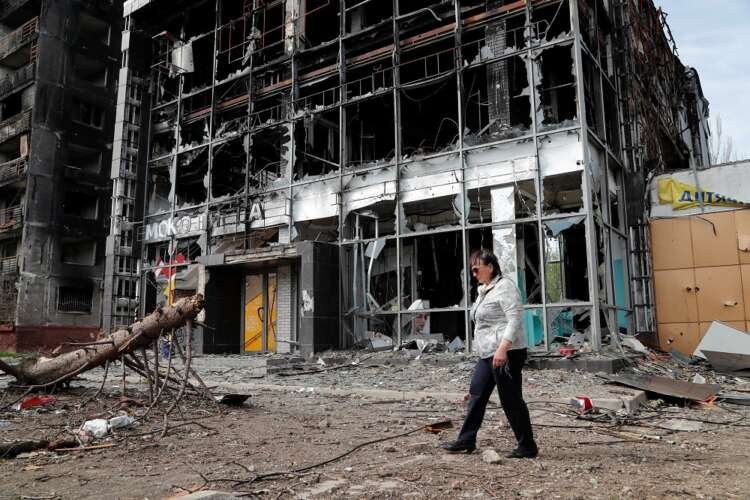 A local resident walks outside a destroyed building in Mariupol