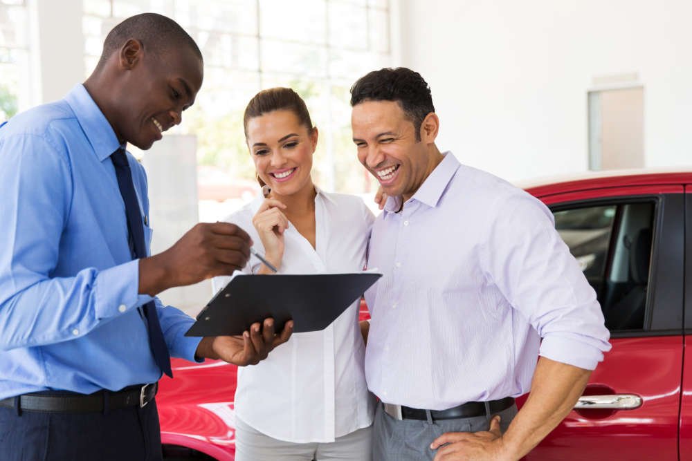 African car dealer explaining negative equity in vehicle finance to a couple - Global Banking & Finance Review
