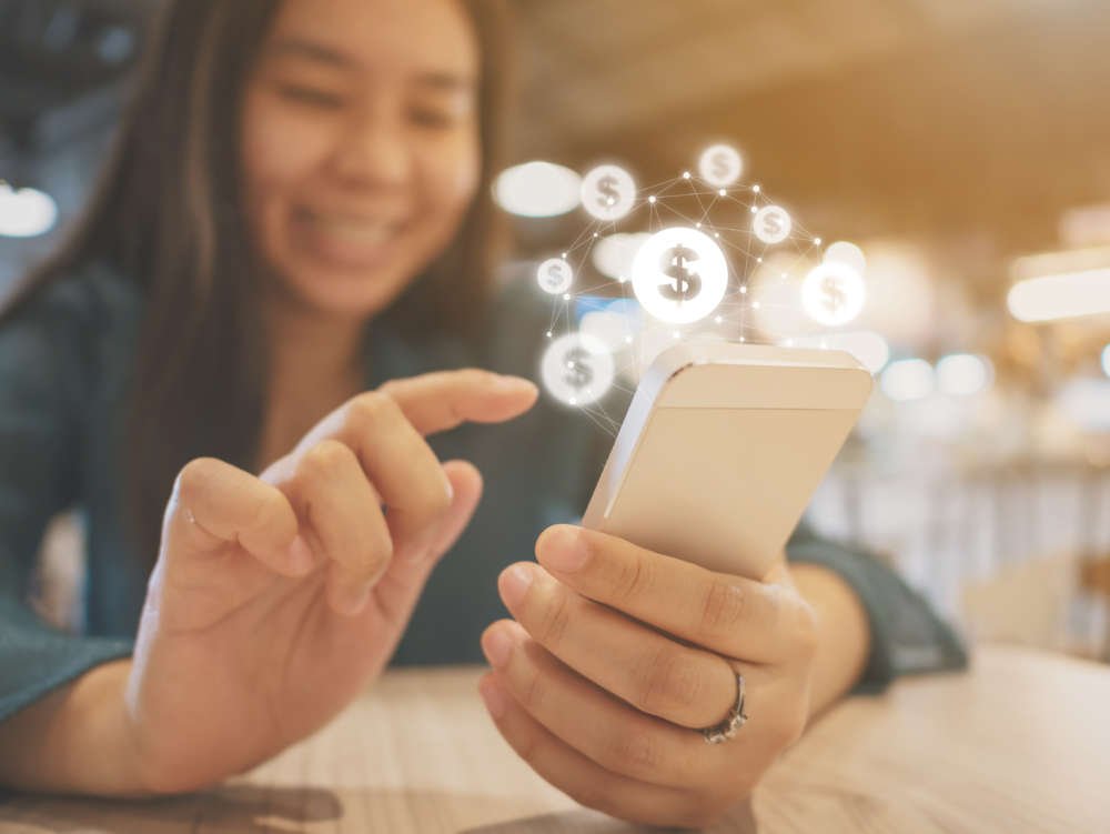 Asian woman using mobile phone for financial transactions amidst SFTR reporting challenges - Global Banking & Finance Review