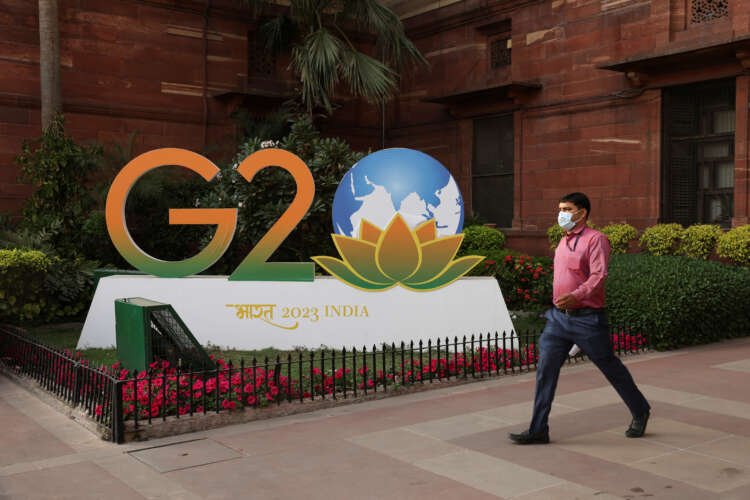 A man walks by a G20 logo model in New Delhi, symbolizing global finance discussions - Global Banking & Finance Review