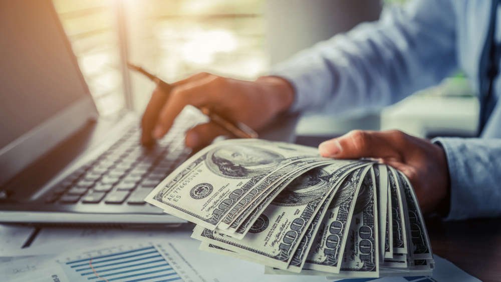 Businessman holding cash, symbolizing digital disruption in finance - Global Banking & Finance Review