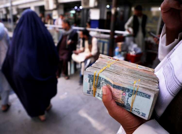 Person holds Afghan banknotes symbolizing the country's economic challenges - Global Banking & Finance Review