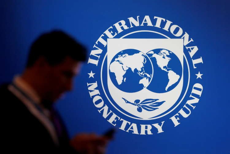 FILE PHOTO: A participant stands near a logo of IMF at the International Monetary Fund – World Bank Annual Meeting 2018 in Nusa Dua