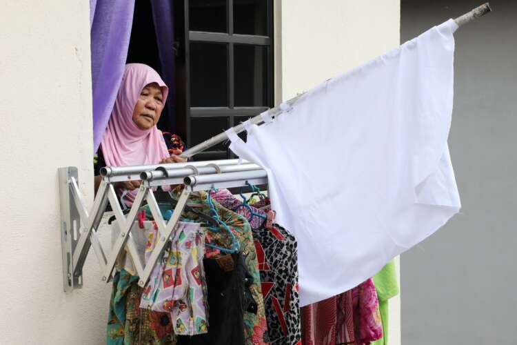 Elderly woman puts away white flag after receiving aid during Malaysia lockdown - Global Banking & Finance Review