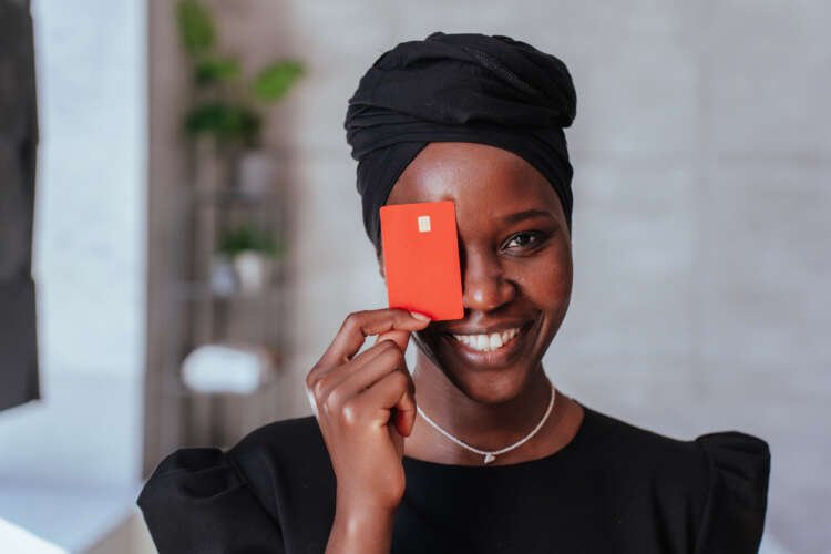 Cheerful African woman with credit card symbolizing hyper-personalization in banking - Global Banking & Finance Review