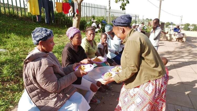 Thandeka Ndlovu hands out plates of food to women at the Ntuzuma community hall in KwaZulu-Natal, South Africa. May 12, 2022. Thomson Reuters Foundation/Kim Harrisberg