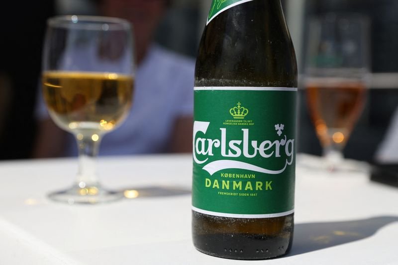 Carlsberg beer logo and beer bottles reflecting profit growth - Global Banking & Finance Review