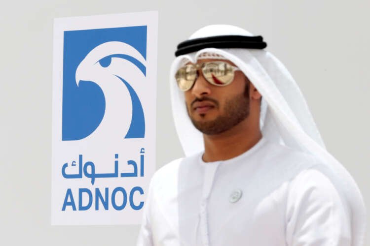 Emirati man near ADNOC logo, showcasing UAE's trade expansion efforts - Global Banking & Finance Review