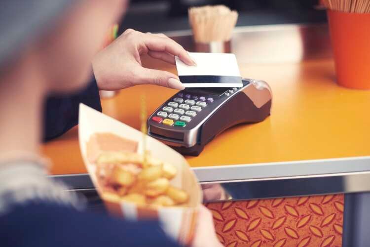 Woman using a contactless card to pay for food, representing payment security myths - Global Banking & Finance Review