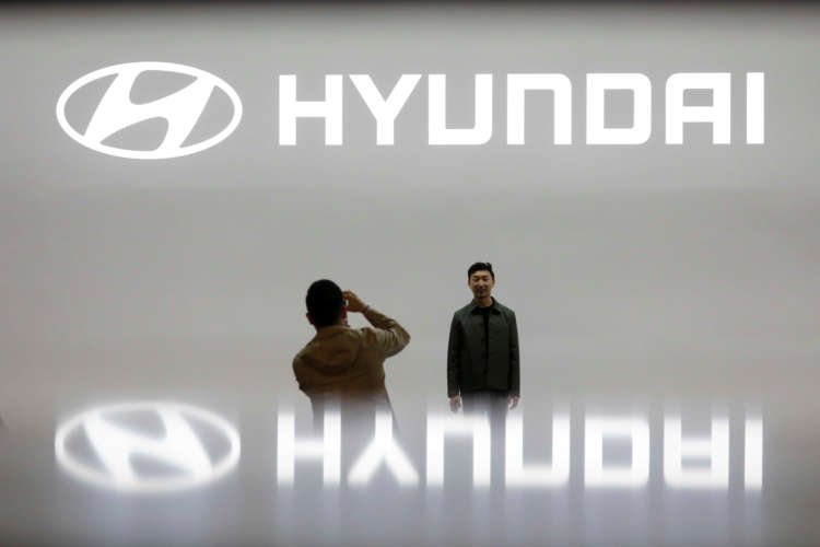 FILE PHOTO: Visitors take photographs in front of the logo of Hyundai Motor during the 2019 Seoul Motor Show