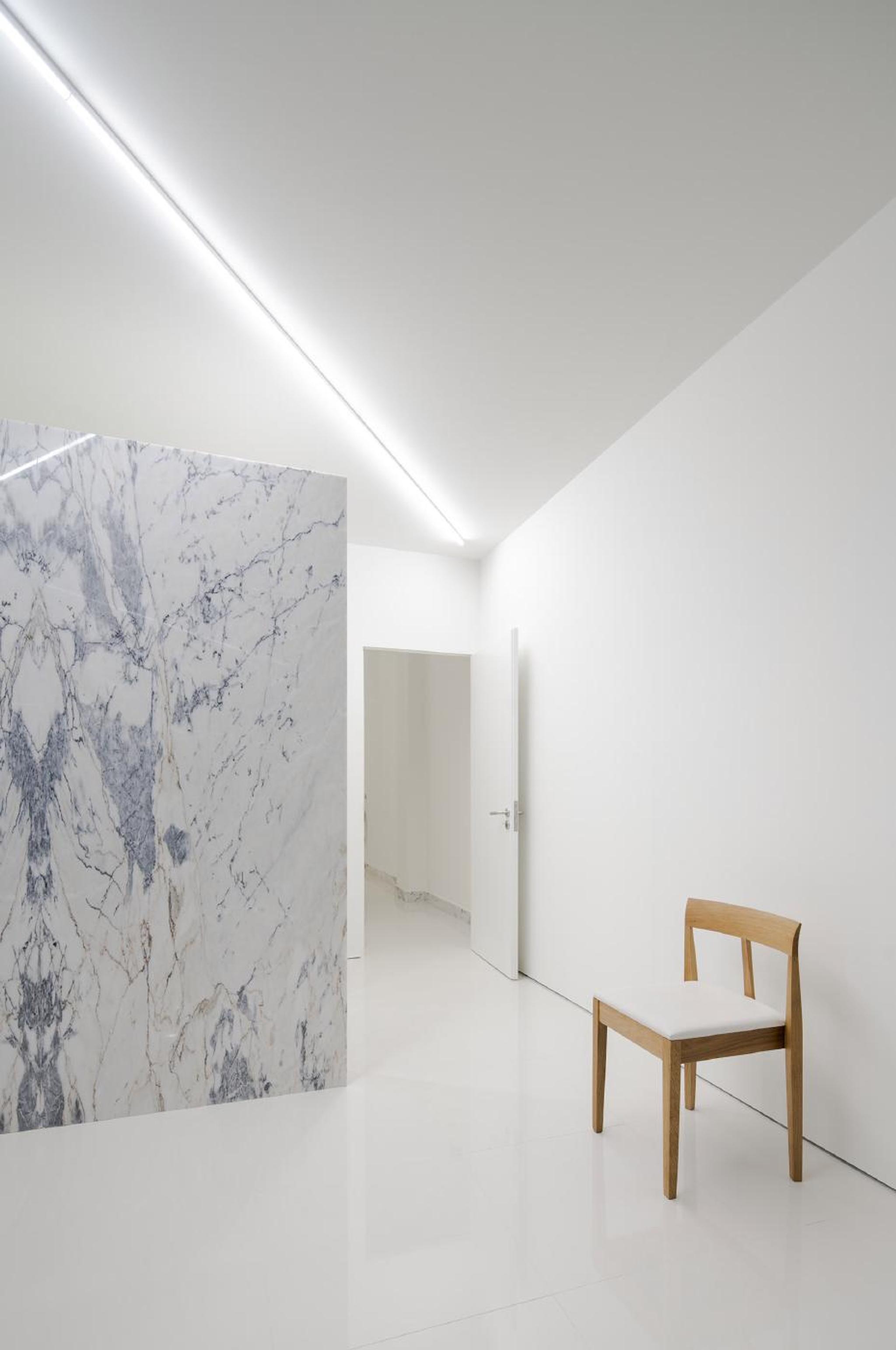 Góc tường ốp đá marble trắng vân xám rõ nét cạnh ghế gỗ