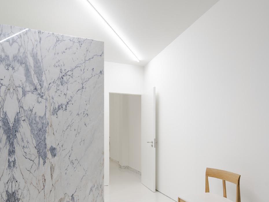 Góc tường ốp đá marble trắng vân xám rõ nét cạnh ghế gỗ