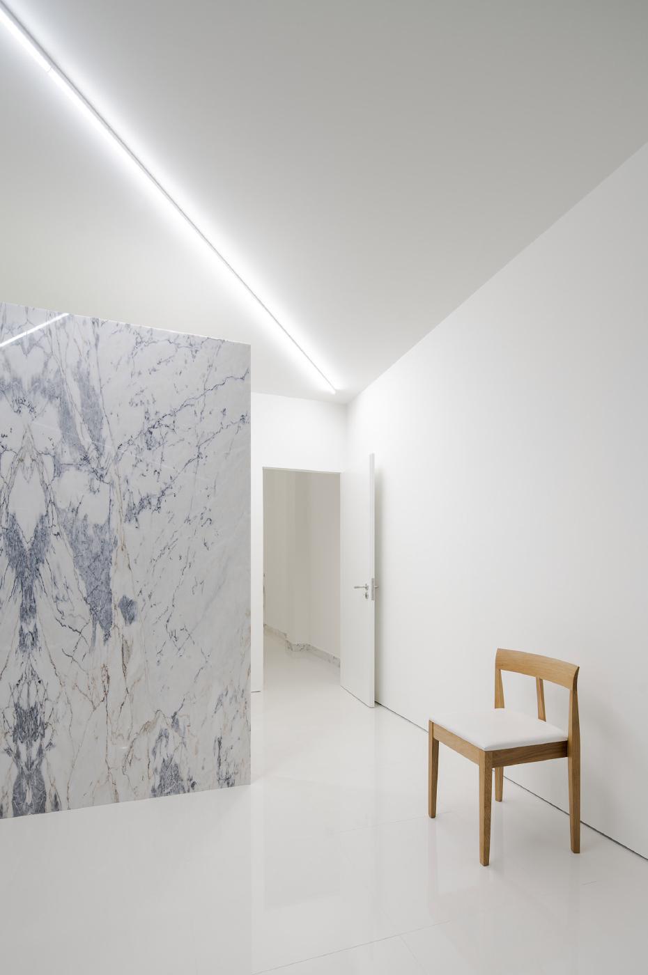 Góc tường ốp đá marble trắng vân xám rõ nét cạnh ghế gỗ