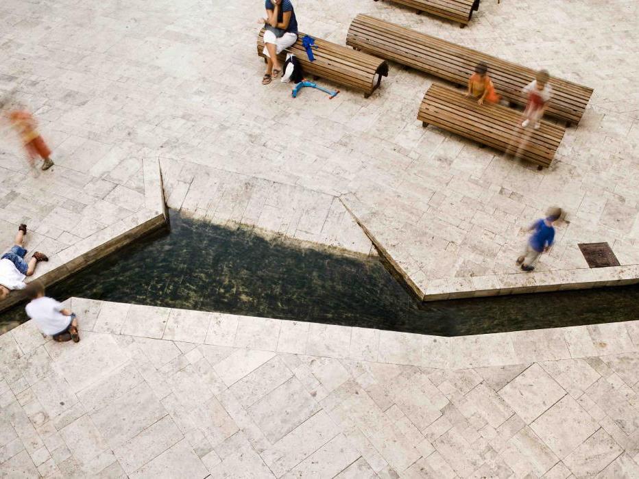 Sân ngoài trời lát đá travertine vàng nhạt với bồn cây đá
