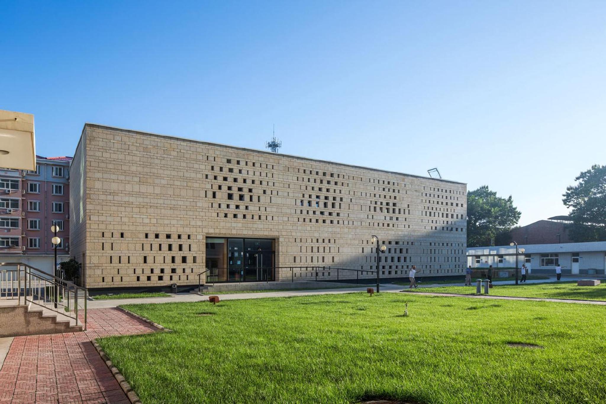 Mặt tiền công trình ốp đá travertine vàng trên thảm cỏ xanh