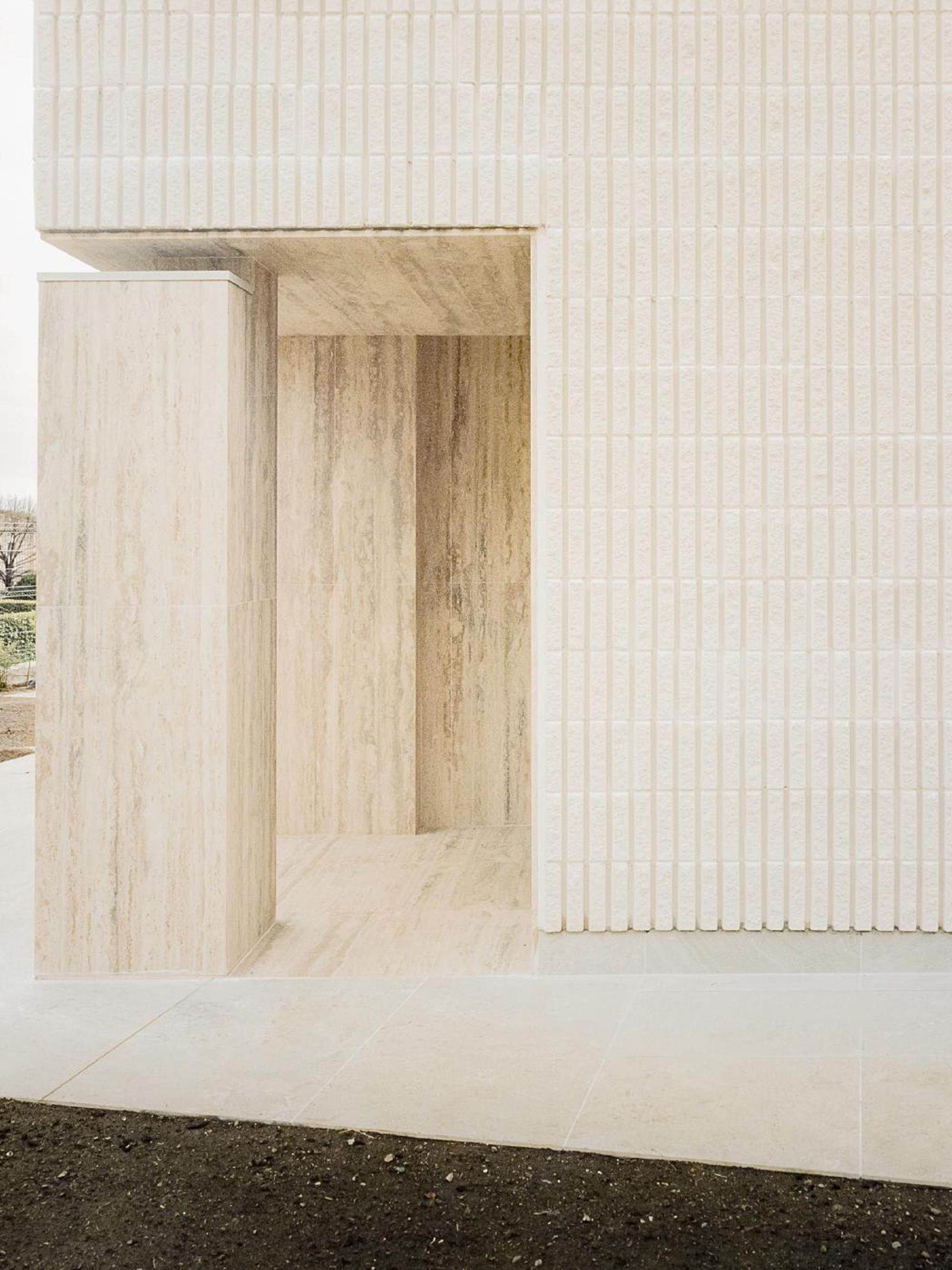 Mặt tường ốp tấm đá travertine kem chia ô đều kiến trúc hiện đại