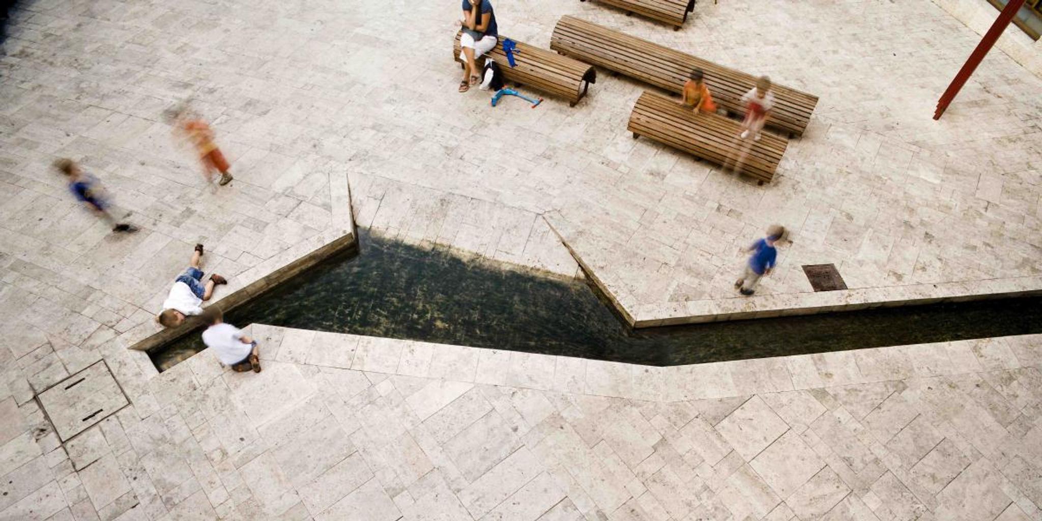 Quảng trường lát sàn đá travertine với ghế băng và người ngồi