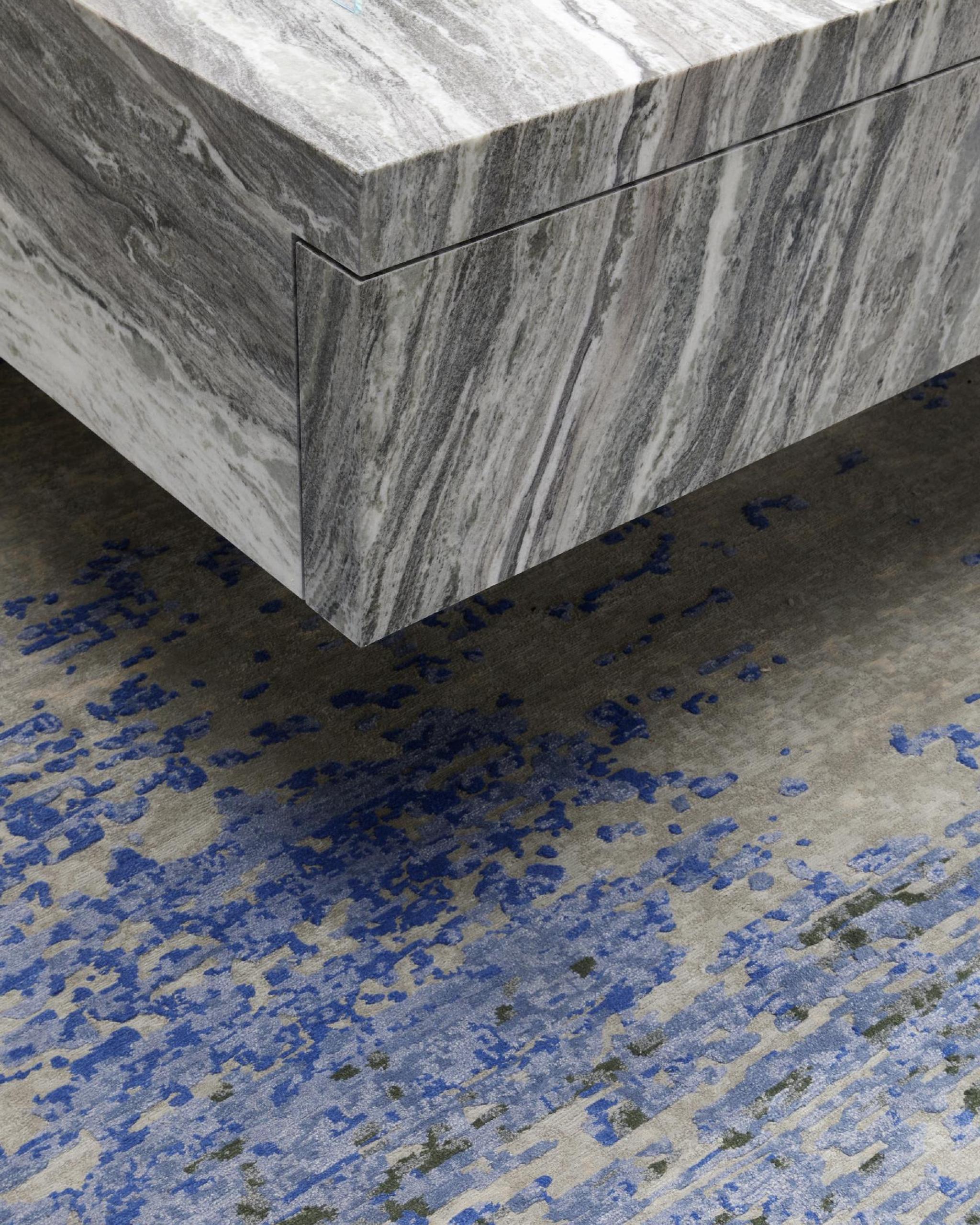 Khối đá marble trắng vân xám đặt trên nền sàn lốm đốm xanh