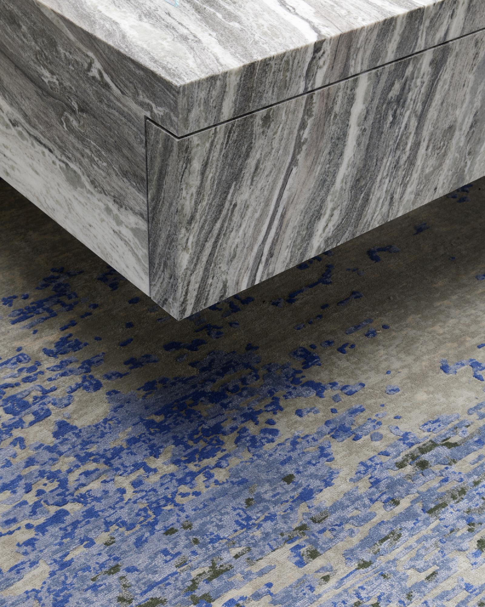 Khối đá marble trắng vân xám đặt trên nền sàn lốm đốm xanh
