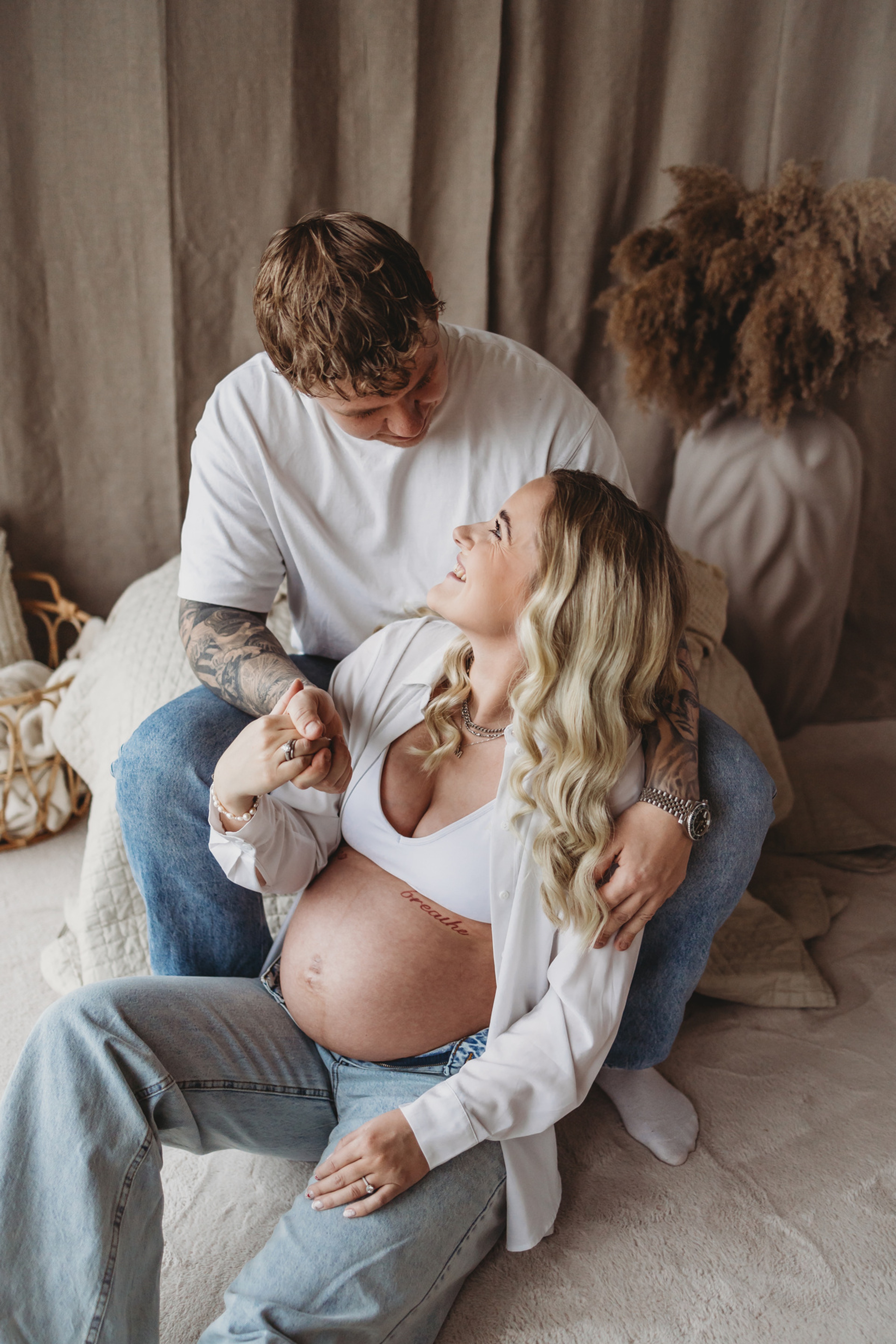 Gravid kvinde og partner i hvidt/creme tøj i studie