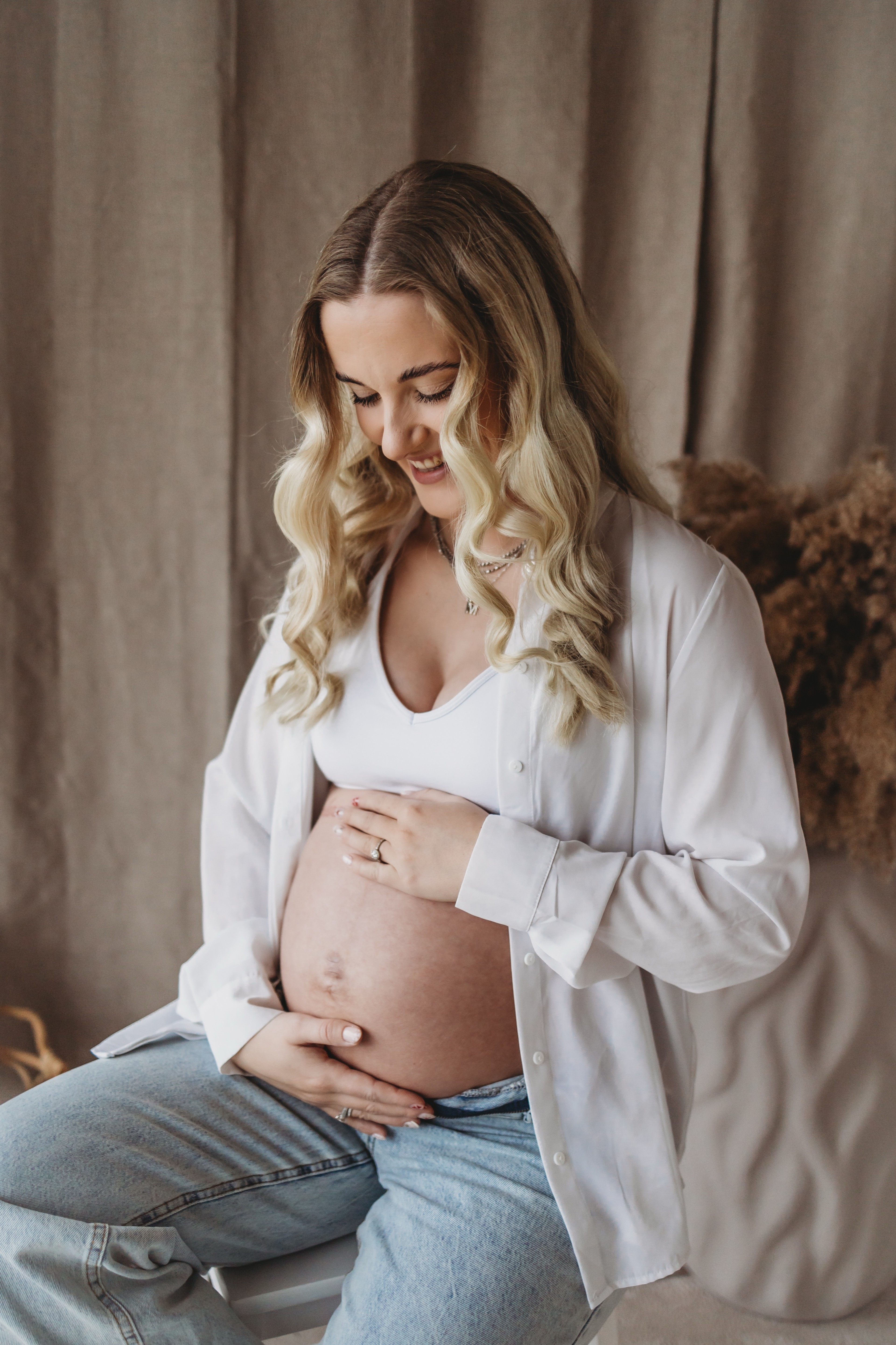 Gravid kvinde holder om maven i hjemmestudiet