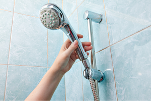 A person reaching for a showerhead in a Wildomar, CA home.